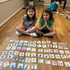 Two children at a First Communion celebration with completed Memory Mix cards spread out in front, showing personalized drawings and messages