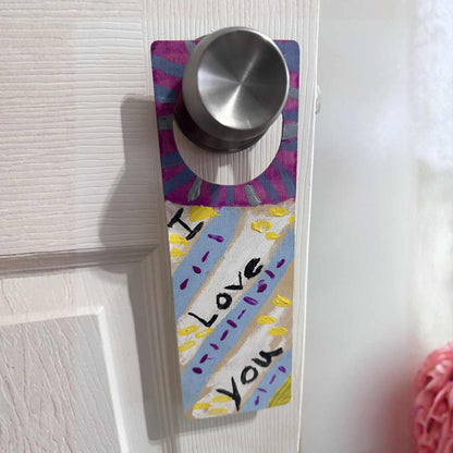 Decorative door hanger with 'I love you' text and colorful design on a white door completed with paint your own door hanger party craft kit